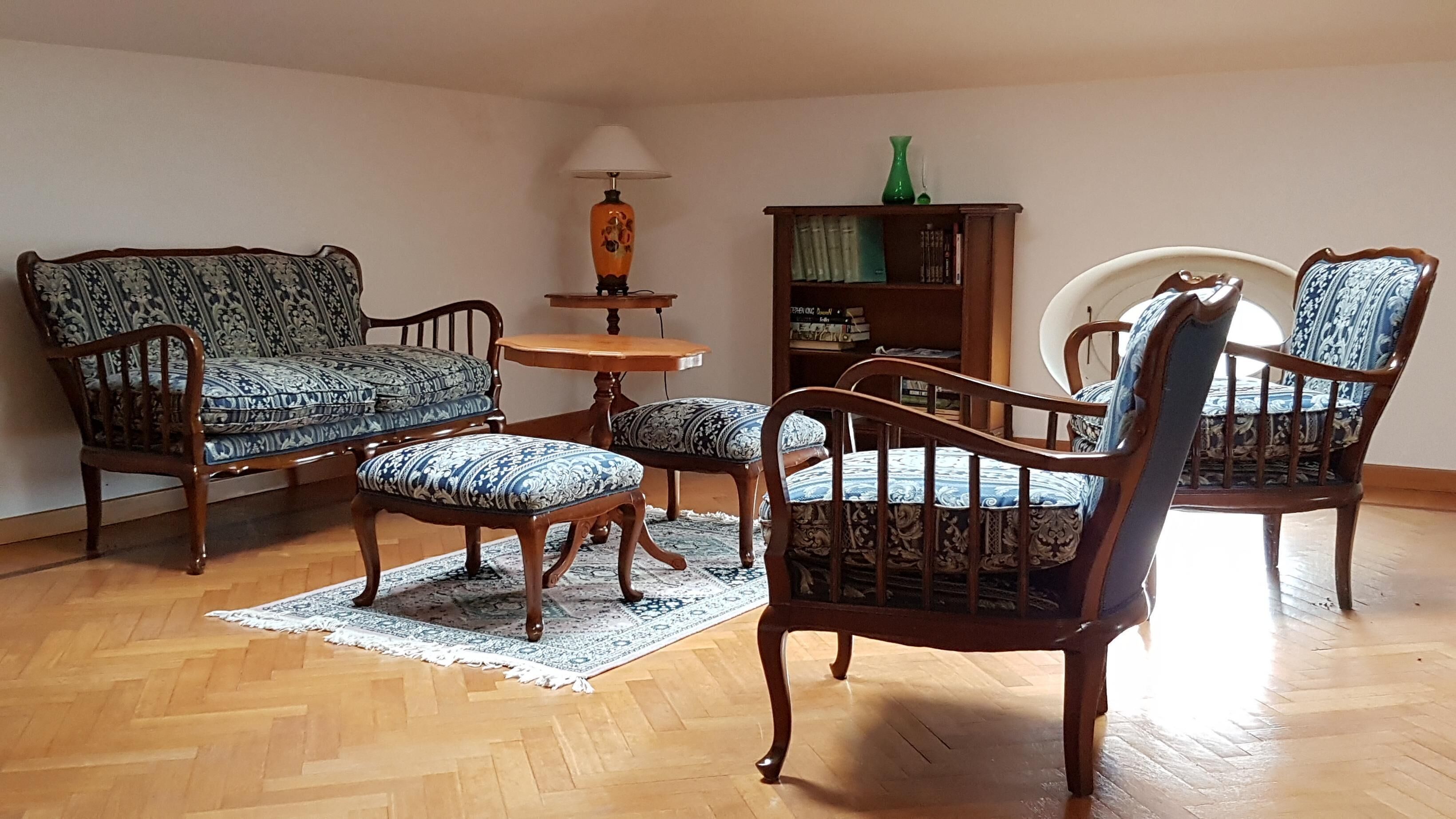 A living room with a sofa, two armchairs, a small table, and a bookshelf.