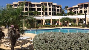 A hotel with a pool, palm trees, and a covered area.