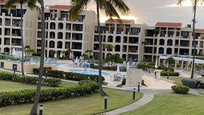 A hotel with multiple floors, a swimming pool, and a well-maintained lawn.