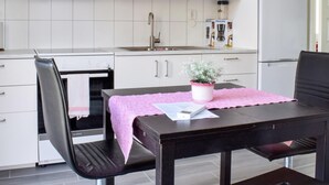 Una cocina moderna con armarios blancos, un lavamanos de acero inoxidable, horno empotrado y refrigerador blanco.
