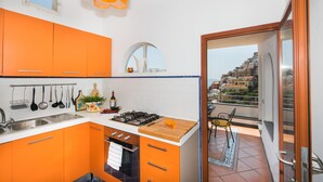 Une cuisine moderne avec des meubles de rangement orange, une cuisinière à gaz et des ustensiles suspendus.