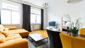 A modern living room with a sofa set, a coffee table, a TV, and a dining table with chairs.