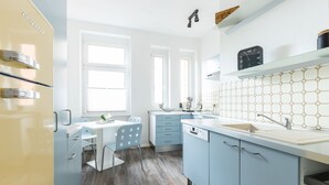 A modern kitchen with light blue cabinets, a white countertop, and a stainless steel refrigerator.