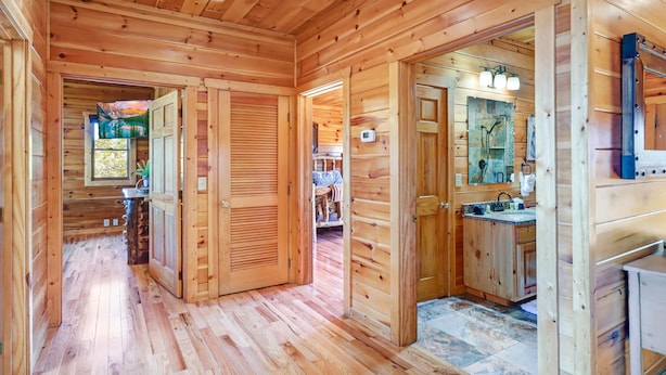 A wooden cabin interior with a hallway leading to a bedroom and a bathroom. - Panoramic View - Suite 2: Brand New Hot Tub - Room w/ French Doors to Porch (sevierville)