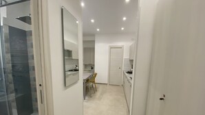 Une cuisine moderne avec des meubles blancs, une table à manger avec des chaises et une cabine de douche en verre.