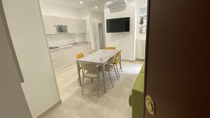 Une cuisine moderne avec des armoires blanches, un four encastré et un téléviseur à écran plat fixé au mur.