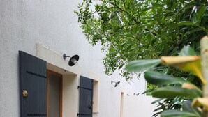 Un bâtiment doté d’une façade en pierre, de deux portes noires avec des panneaux de verre et d’une petite porte en bois.