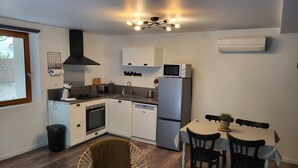 Une cuisine compacte avec des meubles blancs, un four à micro-ondes, un évier et un coin repas comprenant une table et des chaises.