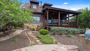 Una casa moderna con un patio de piedra, un espacio exterior cubierto y una parrilla.