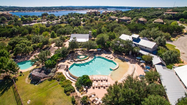 Vista aérea de un resort con varias piscinas, una piscina central grande y villas circundantes.