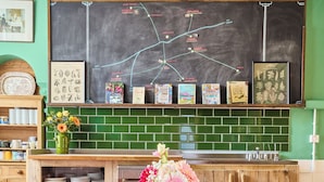 Une table en bois rustique, ornée d’un vase de fleurs, un tableau noir avec une carte, et un mur recouvert de carreaux verts dans une cuisine.