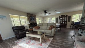 A living room with a sofa, a coffee table, a TV, and a fireplace. - Stilt home close to MacRaes, city dock, Wild Life Park. (Homosassa)