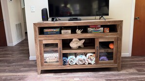 A wooden entertainment center with a flat-screen TV, a speaker, and board games. - Stilt home close to MacRaes, city dock, Wild Life Park. (Homosassa)