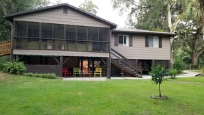A two-story house with large windows, a covered patio, and a staircase leading to the upper level. - Stilt home close to MacRaes, city dock, Wild Life Park. (Homosassa)