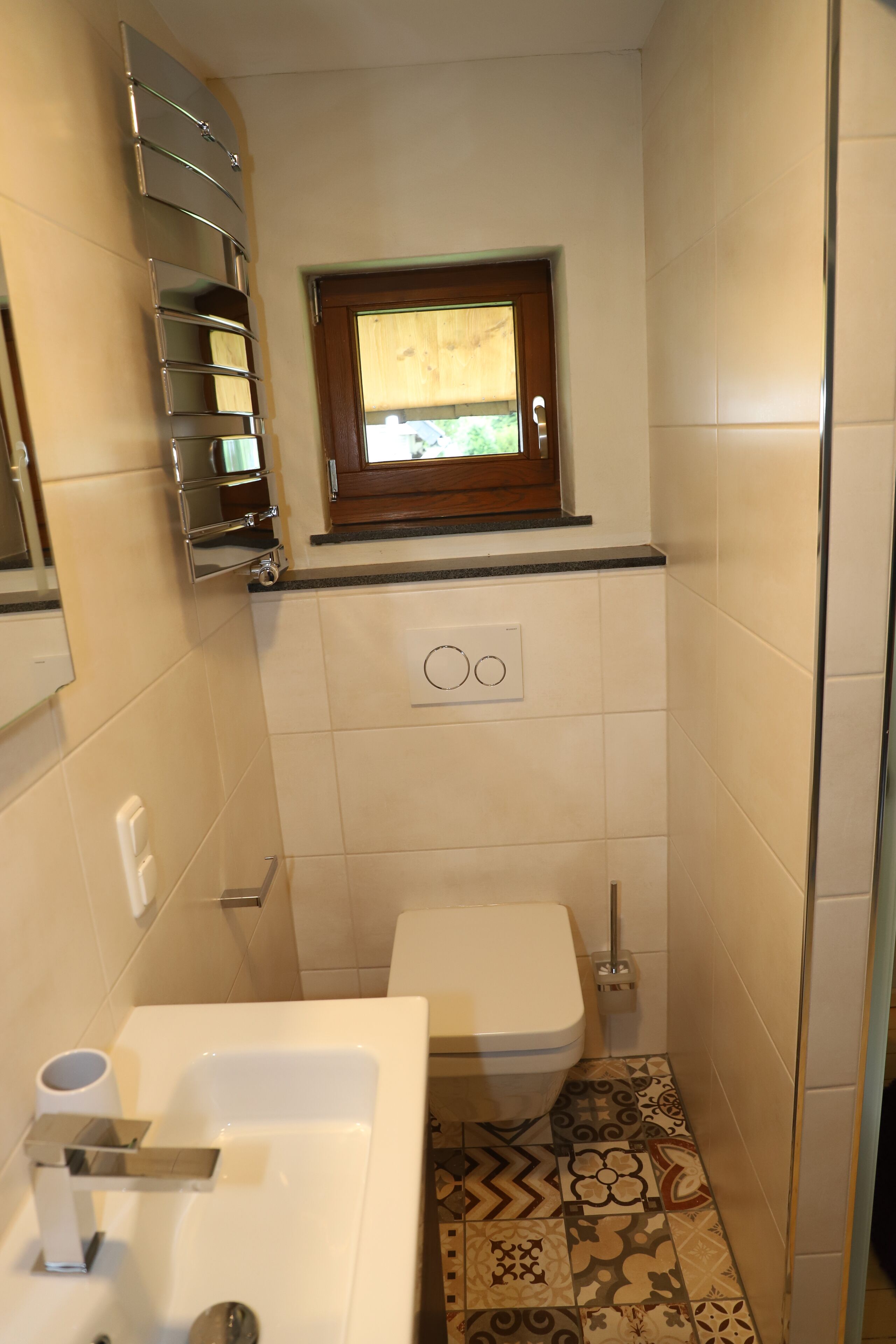 Een kleine badkamer met toilet, bidet en een klein raam boven het toilet.