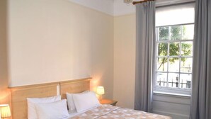 Una camera d'albergo con un letto, due lampade sui comodini, una finestra con tende e vista sull'esterno.