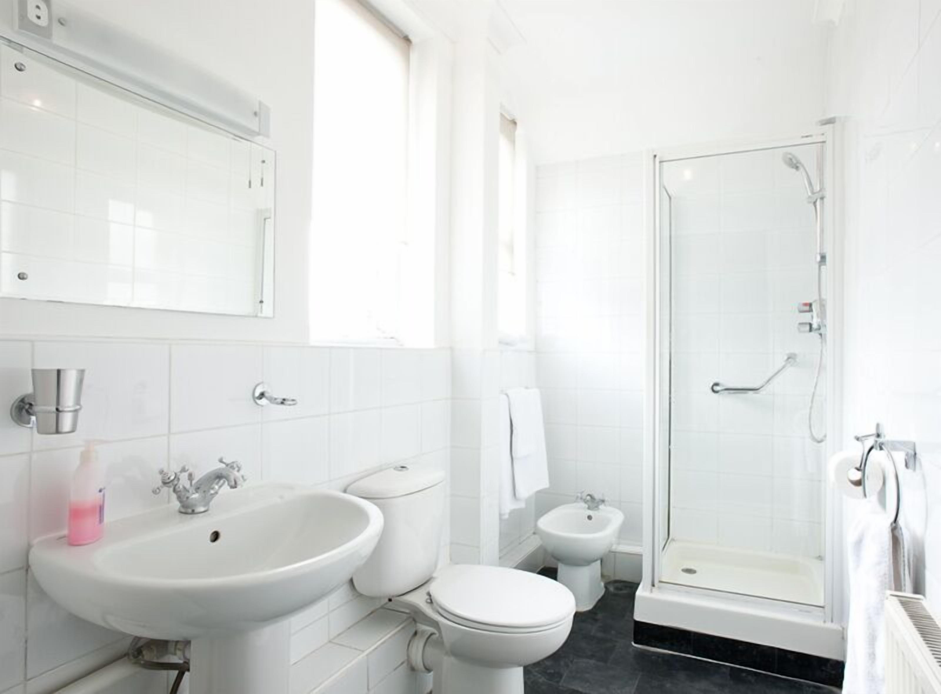 Een moderne badkamer met een wastafel, toilet, bidet en douchecabine.