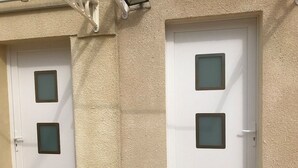 Zwei weiße Türen mit gefrosteten Glasscheiben in einer beige strukturierten Wand.
