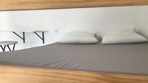 Ein Etagenbett mit grauem Matratze und zwei Kissen.