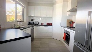 A modern kitchen with white cabinets, a stainless steel refrigerator, and a built-in oven. - Modern Townhouse close to CBD (Bendigo)