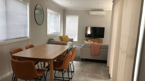 A modern living room with a dining table, chairs, a sofa, and a TV. - Modern Townhouse close to CBD (Bendigo)