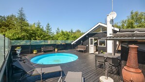 Uma área de piscina no terraço com hidromassagem, espreguiçadeiras e um pérgola.