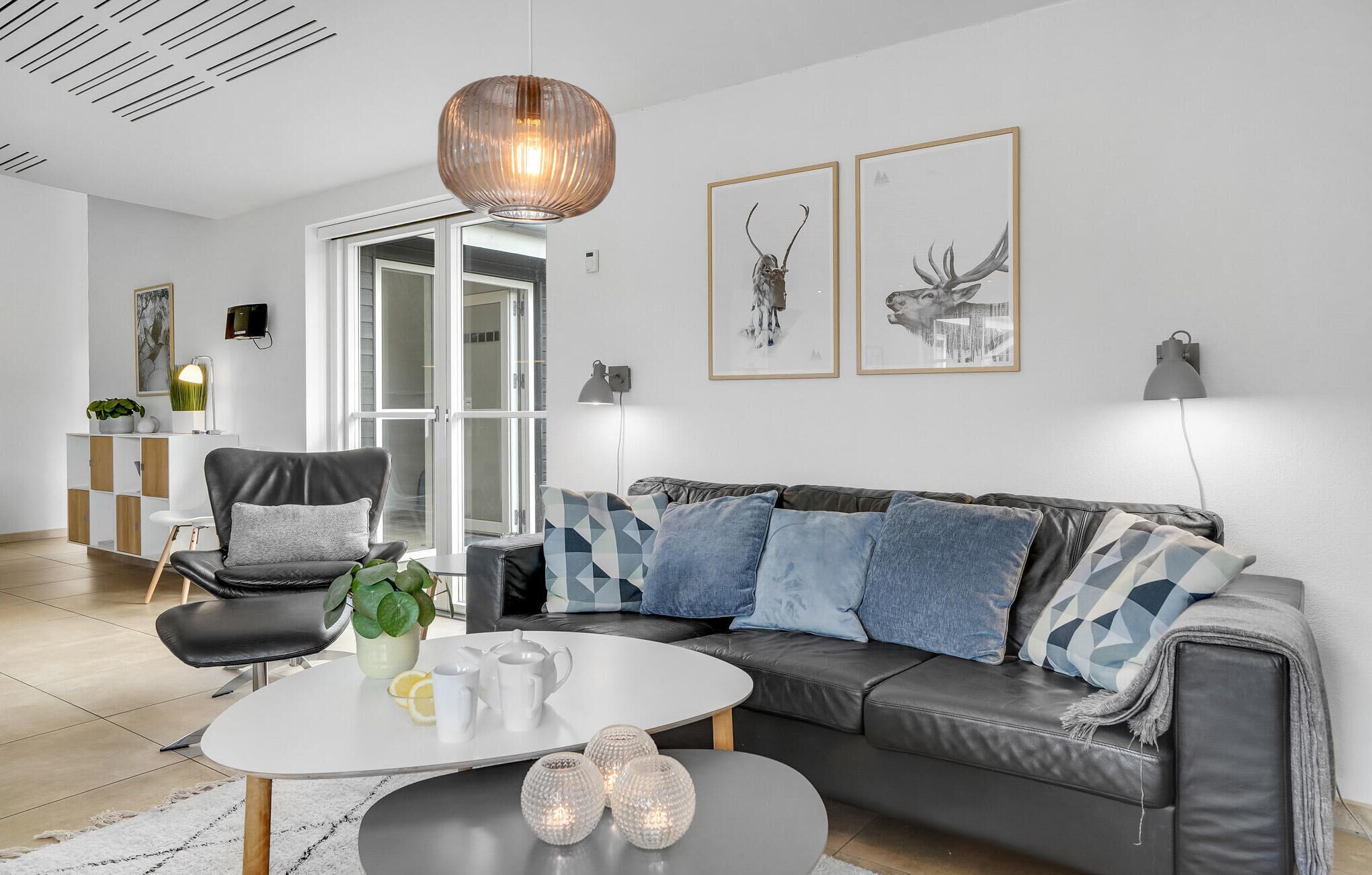 En moderne stue med en lædersofa, et hvidt sofabord og et glaskab.