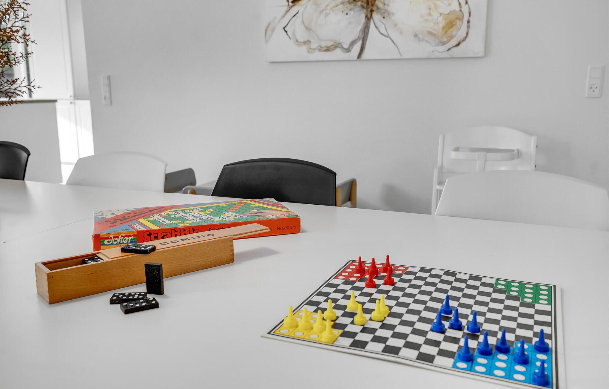 A meeting room with a white table, Scrabble game, and a checkered board game.