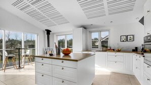 A spacious kitchen with white cabinetry, a large island, and a view through the windows. - Awesome home in Blåvand with sauna (Blåvand)