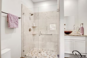 A modern bathroom with a glass-enclosed shower, a vanity with a large mirror, and a toilet. - Lavender - Private Getaway with Horseshoes, Stargazing, and Walking Trails (Wimberley)