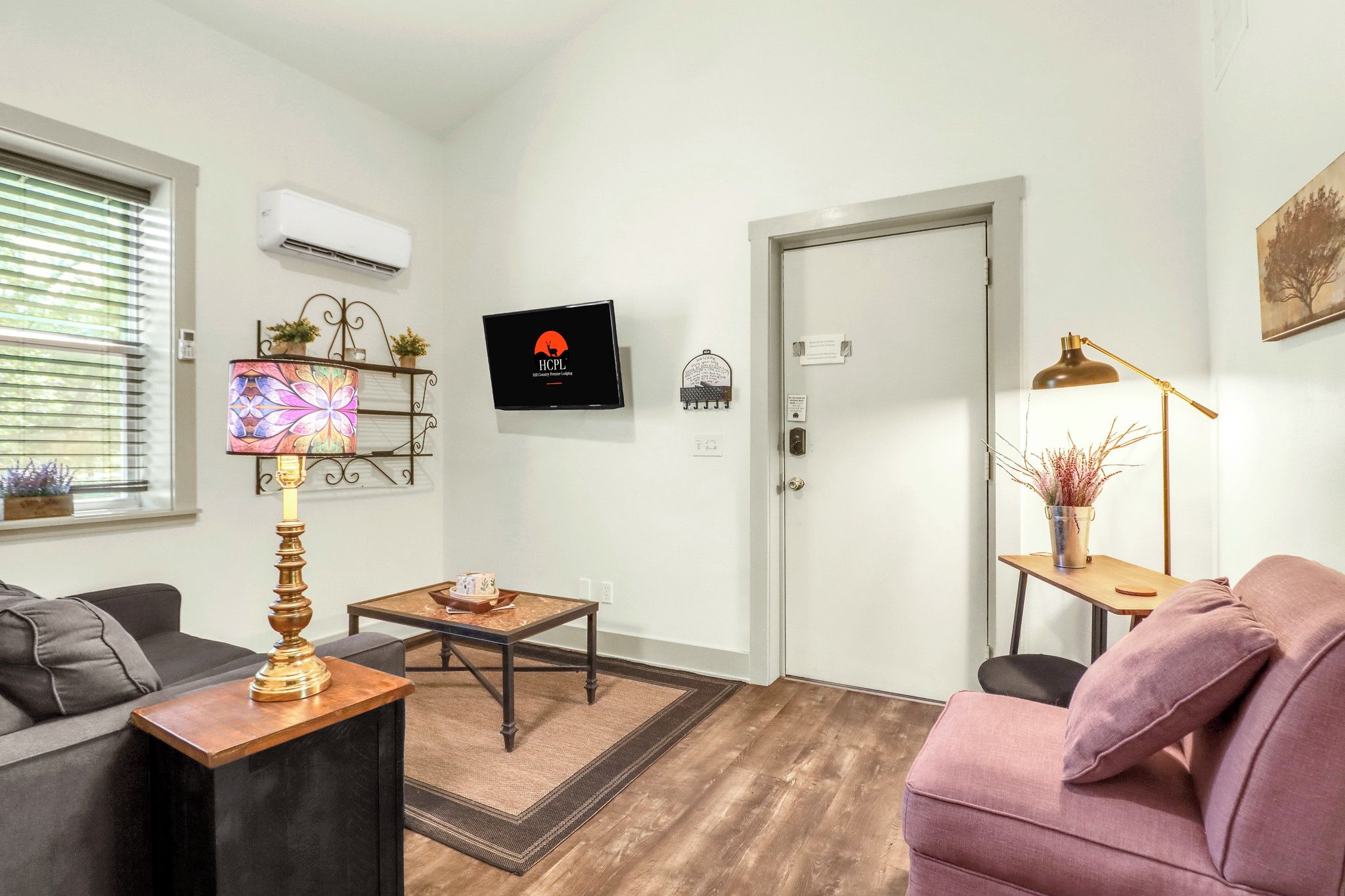 Een moderne woonkamer met een bank, een salontafel, een lamp en een deur.