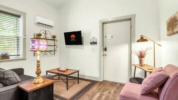 Een moderne woonkamer met een bank, een salontafel, een lamp en een deur.