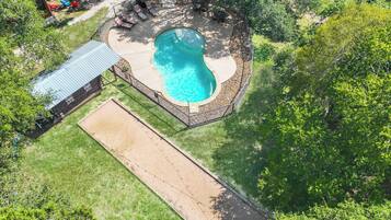 A circular swimming pool surrounded by a stone deck, with a covered patio area and outdoor seating.