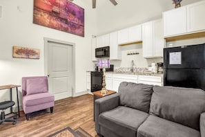 A modern apartment with a living room, kitchenette, and a dining area. - Lavender - Private Getaway with Horseshoes, Stargazing, and Walking Trails (Wimberley)
