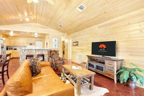 A cozy wooden interior with a sofa, armchair, and TV in a living area.