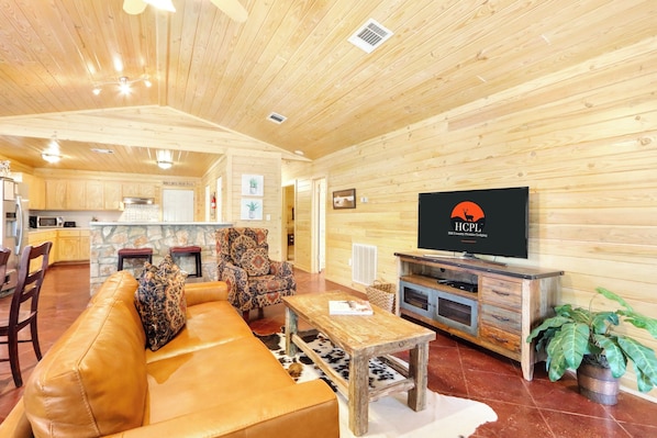 A cozy wooden interior with a sofa, armchair, and TV in a living area.