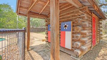 A rustic wooden cabin with a metal fence in the foreground.
