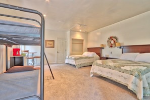 A room with two single beds, a bunk bed, a desk with a chair, and a small table.