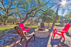 An outdoor seating area with Adirondack chairs and a stone fire pit.