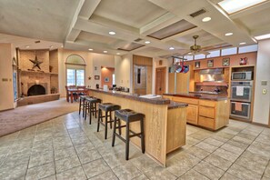 A spacious kitchen with a central island, bar stools, a fireplace, and modern appliances. - Four Bedroom Ranch House with Swimming Pool Access on 75 Acres (Wimberley)