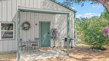A metal shed with a green door, a small table with chairs, and a wreath on the wall.