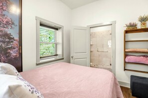 Un dormitorio con cama, ventana, puerta y repisa con toallas.
