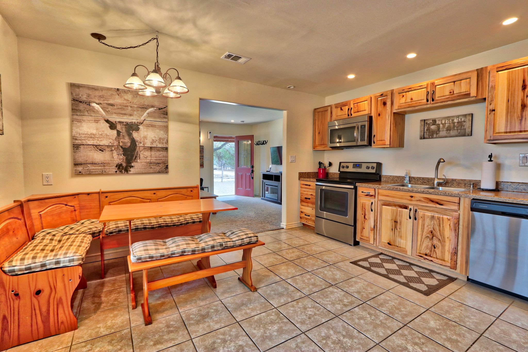 A kitchen with wooden cabinets, a dining area with a bench, and a large painting on the wall.