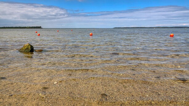 A clear beach with pebbles, a rock, and several orange buoys in the water. - 4 bedroom cozy home in Boiensdorf (Boiensdorf)