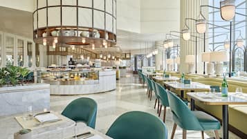 A modern hotel lobby with a central bar, seating areas, and large windows.