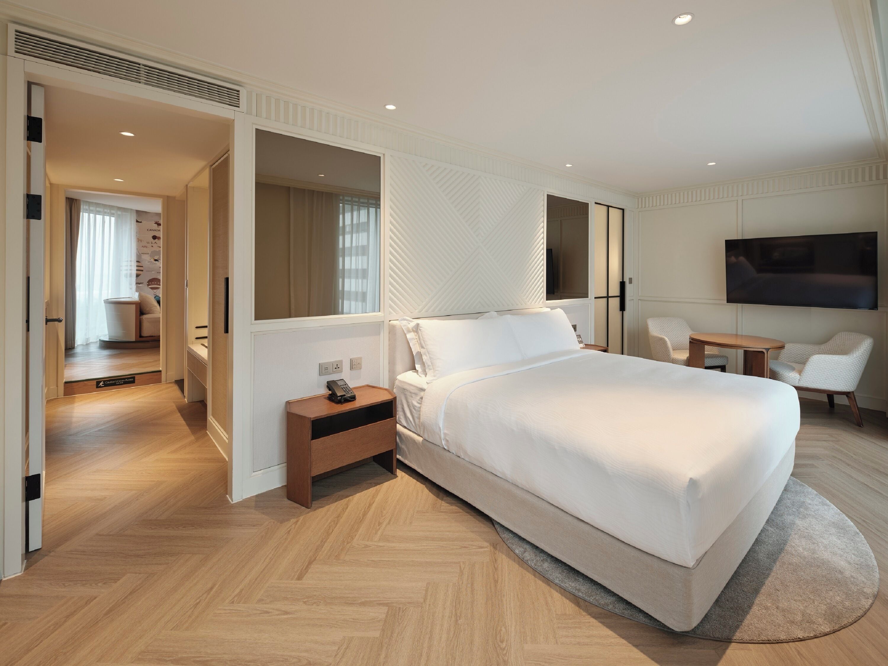 A modern hotel room with a large bed, bedside table, and a TV mounted on the wall.