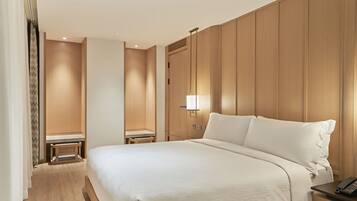 A hotel room with a large bed, a bedside table with a lamp, and a wooden panel wall.