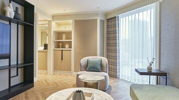 A modern hotel room with a sofa, a round coffee table, a bed, and a small side table.