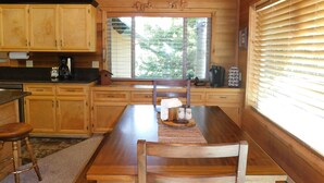 Un intérieur en bois comprenant une table à manger, des chaises, un ventilateur de plafond et une grande fenêtre.