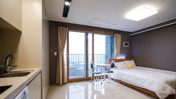 Hotelkamer met een bed, een tafeltje met stoelen, een wastafel en een balkon met uitzicht.